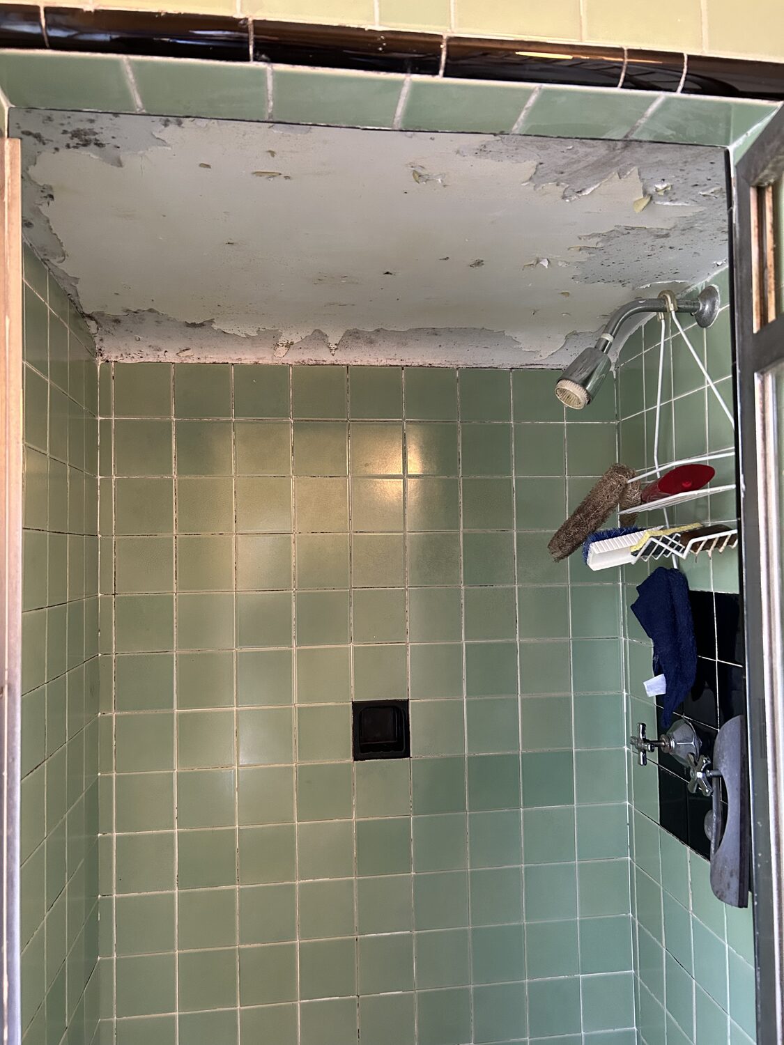 Shower ceiling with peeling paint above green tile before repair