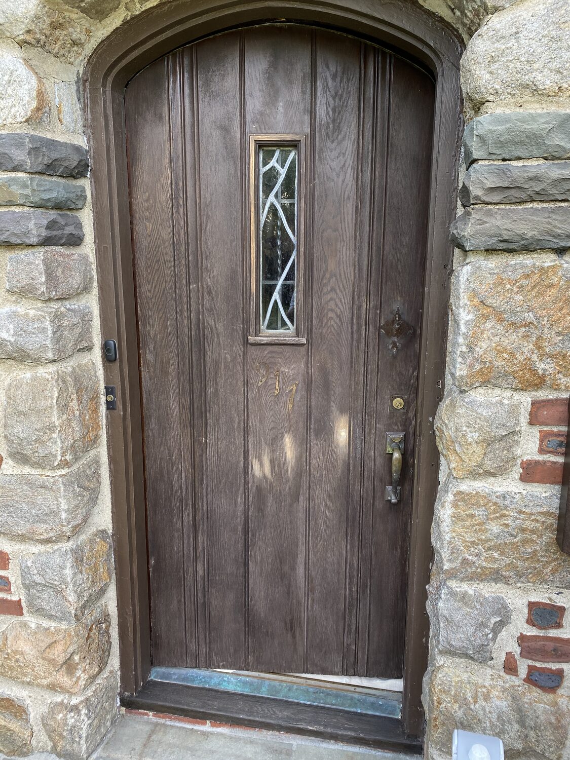 Weathered arched wood front door before refinishing